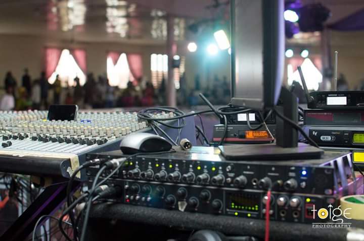 Live event sound setup with mixer, interfaces, and event hall in the background